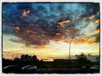 Road passing through city against cloudy sky