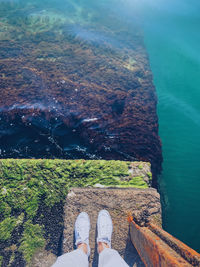 Low section of person in sea by mountains