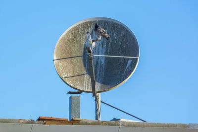 Low angle view of telephone pole against clear blue sky