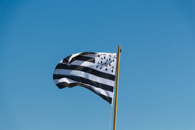 Low angle view of flag against clear blue sky