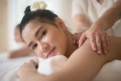 Portrait of smiling young woman being massaged on table in spa