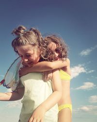 Low angle view of boy and girl against blue sky