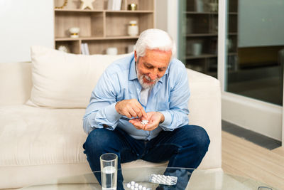 Young man using mobile phone while sitting on sofa at home