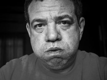 Close-up portrait mature man making face in darkroom