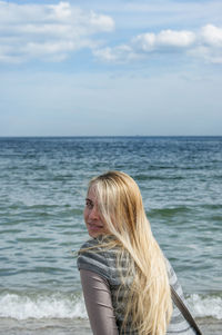 Side view portrait of young woman at beach against sky