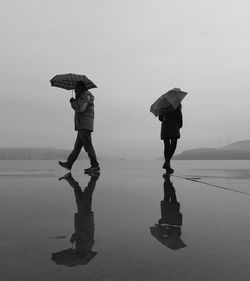 Man and woman walking on wet road during rainy season