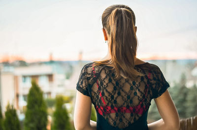 Woman looking away while standing against sky