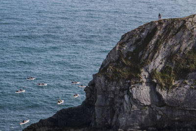 People on cliff looking at boat race in sea