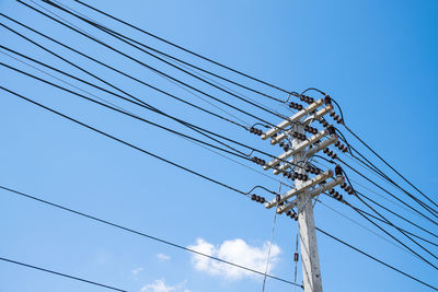 Low angle view of electricity pylon against clear blue sky