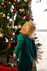 Cute little kid looks at christmas tree decorated with toys and garland. new year and christmas. 