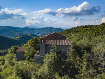 House and trees on mountain against sky