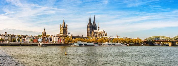 Buildings by river against sky