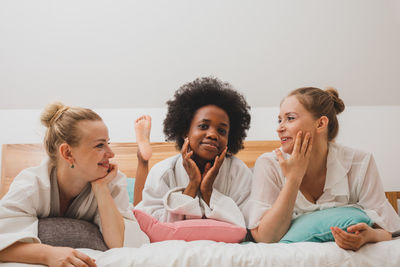 Female friends sitting on bed at home