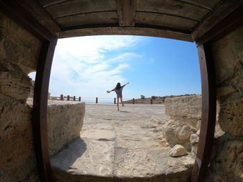 Rear view of man standing on rock against sky