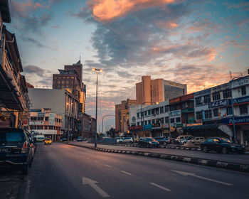 View of city street and buildings at sunset