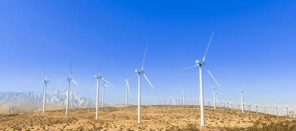 Wind turbines on field against clear blue sky