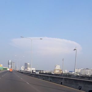 Vehicles on highway against sky in city