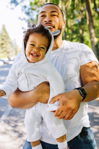 Man carrying happy toddler son at park