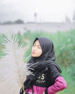 Young woman standing against plants