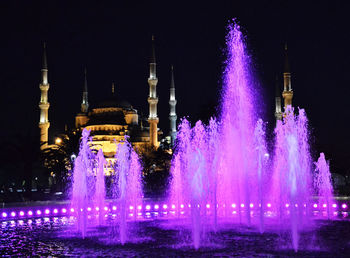 Illuminated fountain building against sky at night