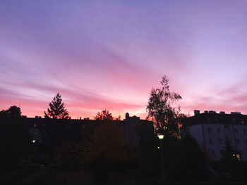 Silhouette trees and buildings against sky at sunset