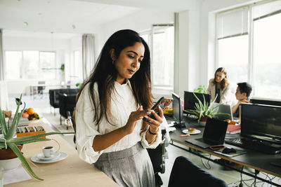 Female business professional surfing net on smart phone at office