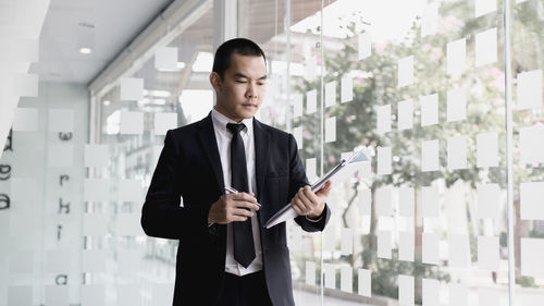 Businessman holding document while standing in office