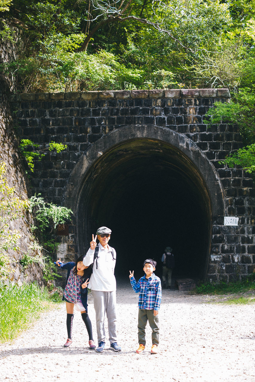 childhood, boys, arch, real people, girls, full length, day, togetherness, leisure activity, family, outdoors, walking, bonding, standing, built structure, architecture, casual clothing, family with two children, child, lifestyles, son, happiness, men, vacations, building exterior, tree, people