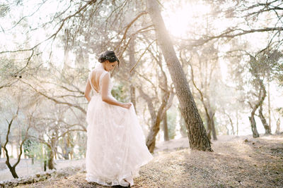 Side view of woman standing against trees