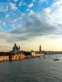 River and buildings against sky during sunset