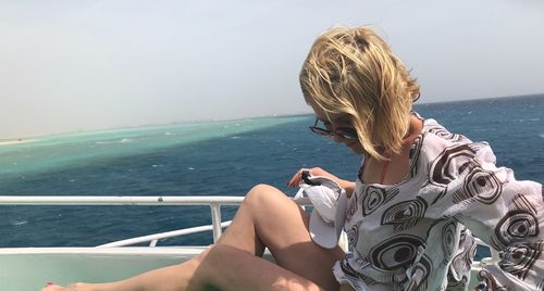 Woman sitting on boat in sea against clear sky