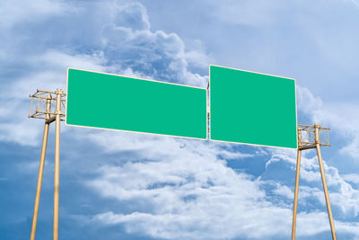 Low angle view of blank road sign against cloudy sky