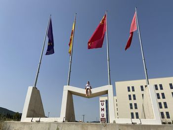 Low angle view of flags against buildings against clear sky