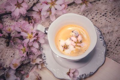 High angle view of a cup of coffee on table with spring flowers 