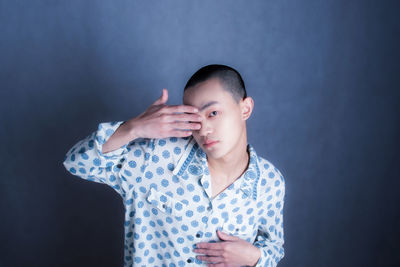 Portrait of young woman standing against wall