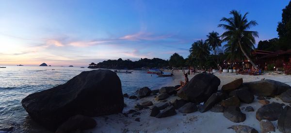 Panoramic view of rocks on beach against sky during sunset