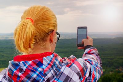 Hiking blonde woman taking photo with smart phone at mountains.