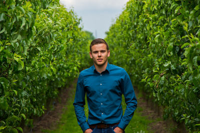 Young man standing against plants