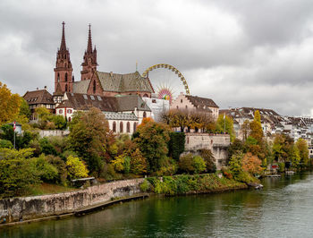 Buildings by river against cloudy sky