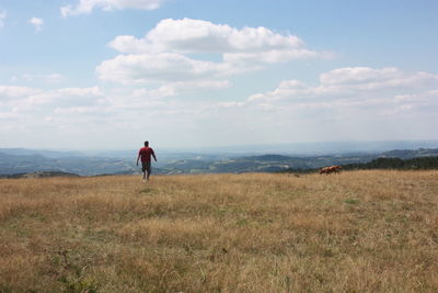 Man walking on field against sky