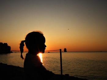 Girl looking at sea during sunset