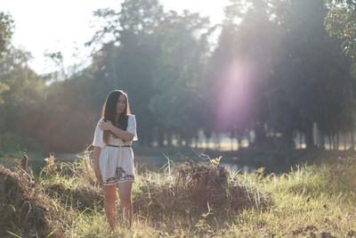 Rear view of woman standing by grass against sky