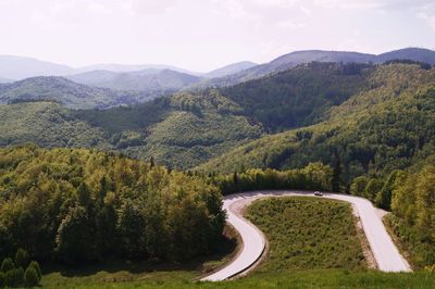 Scenic view of road by mountains against sky
