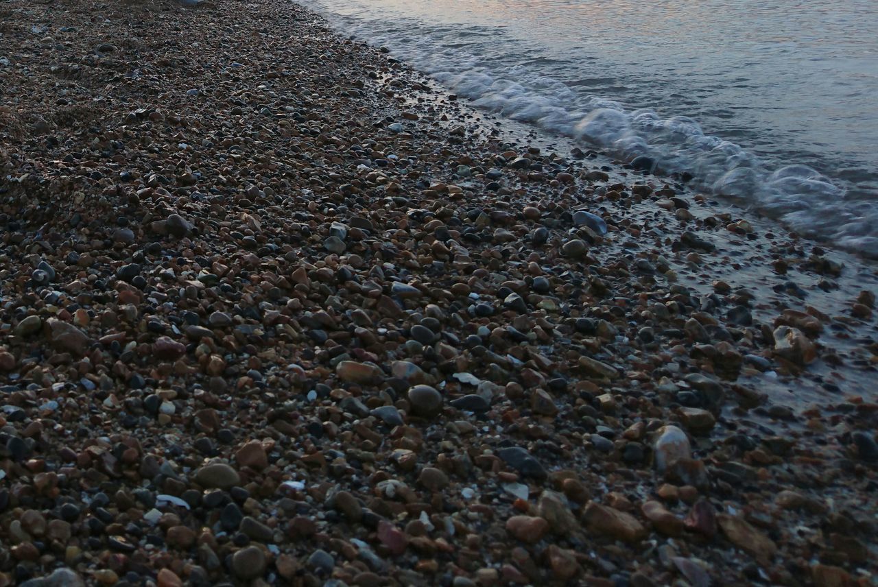 water, beach, sea, pebble, shore, stone - object, tranquility, high angle view, nature, surface level, sand, wet, day, outdoors, beauty in nature, tranquil scene, no people, rock - object, scenics, asphalt