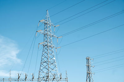 Low angle view of electricity pylon against blue sky