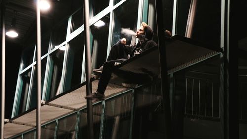 Low angle view of people sitting on staircase at night