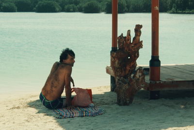 Man sitting on beach by sea