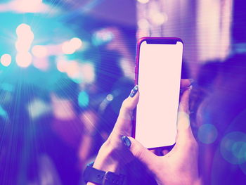 Cropped hand of woman holding mobile phone at concert