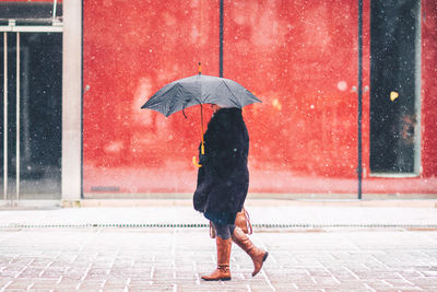 Full length rear view of man with umbrella