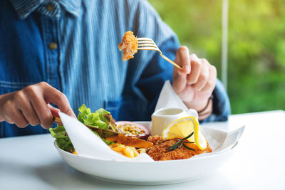 Closeup image of a woman eating fish and chips on table in the restaurant